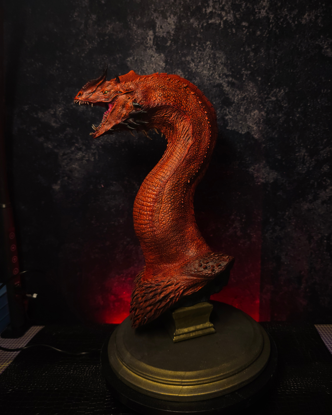 Vue intégrale du buste de dragon rouge inspiré de Caraxes avec long cou serpentiforme, peinture artisanale et socle bronze dans une ambiance gothique.