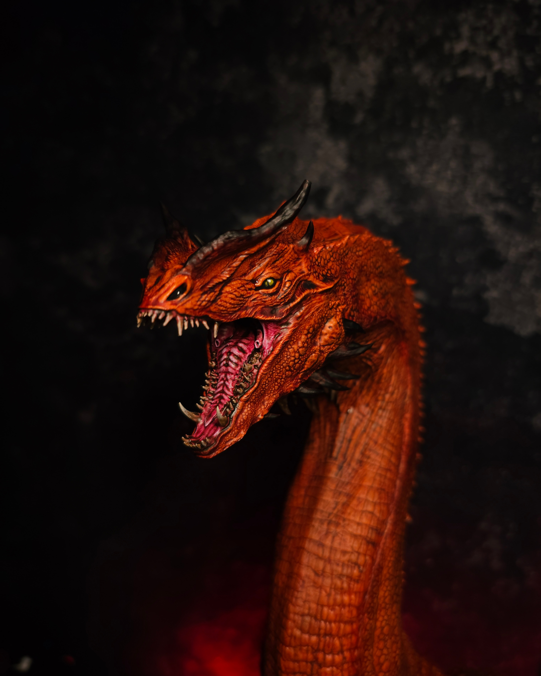 Vue frontale d’un buste de dragon rouge inspiré de Caraxes avec gueule ouverte, long cou et socle bronze dans une décoration fantasy sombre.