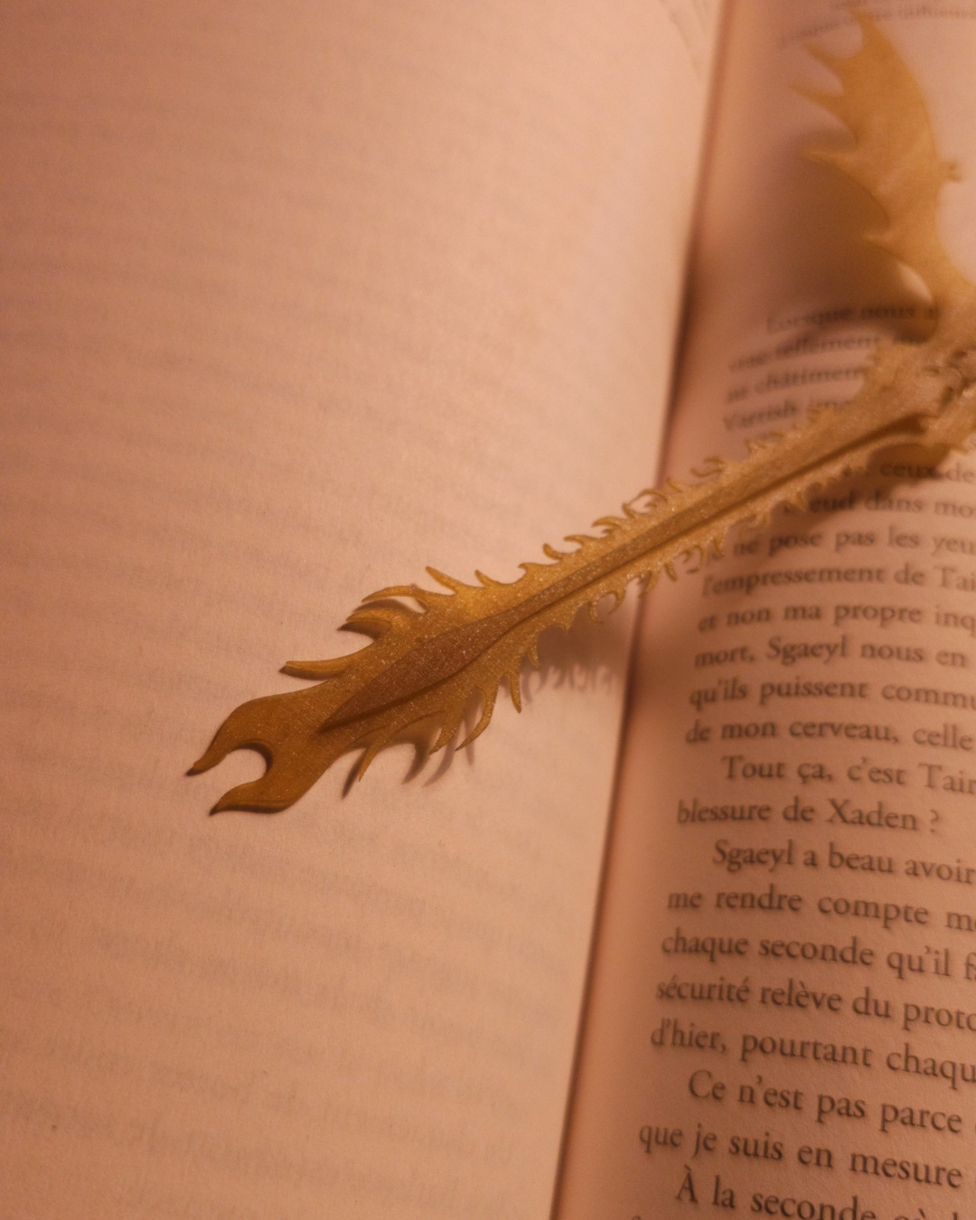 Gros plan sur la queue sculptée du marque-page dragon Gold Feathertail. La résine dorée laisse apparaître des reflets métalliques et un design inspiré d’Andarna. Idéal pour illustrer la finesse d’une figurine de dragon adaptée en accessoire de lecture fantasy.