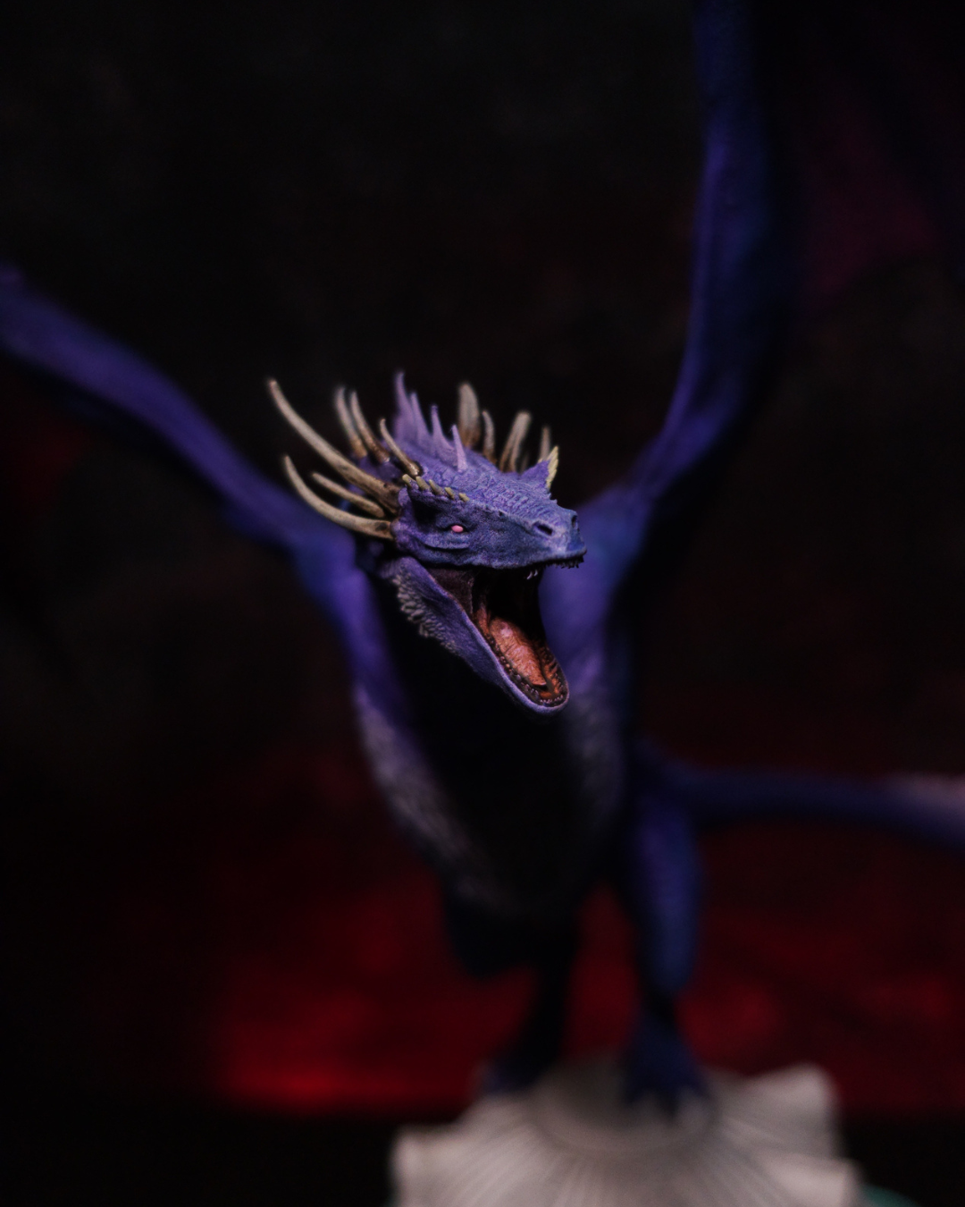 Vue rapprochée de la tête de Dreamfyre, dragon de House of the Dragon, avec ses cornes dorées, ses écailles violettes et sa gueule ouverte aux dents acérées.