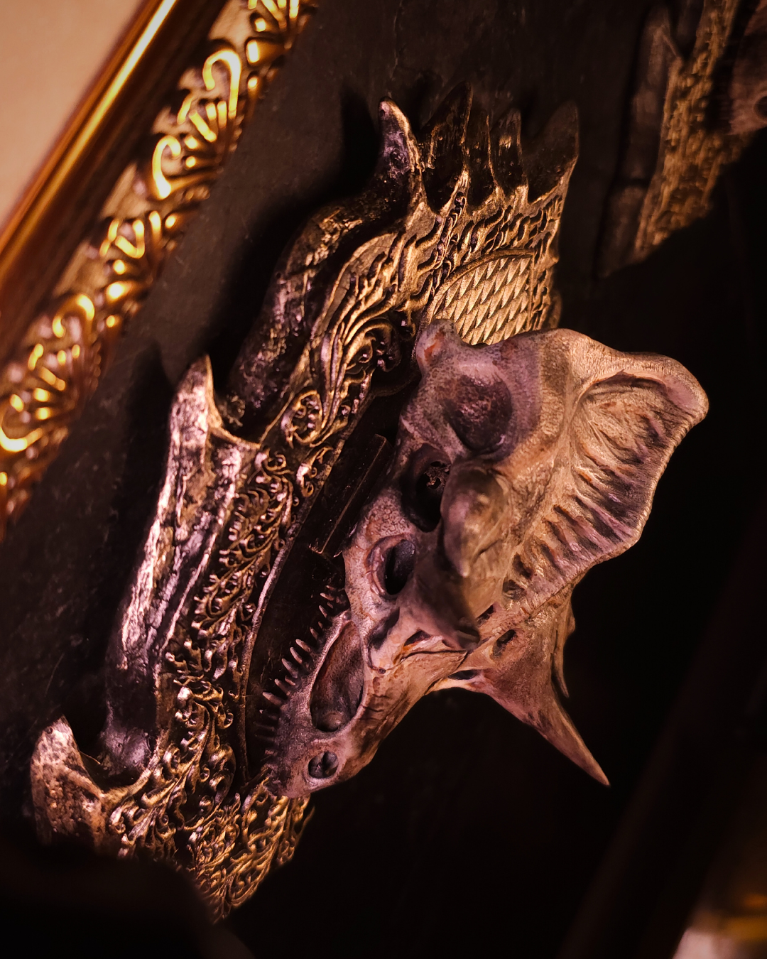 Vue latérale du crâne de dragon Caraxes monté au mur, mettant en valeur la profondeur du relief et la silhouette agressive du dragon dans un décor gothique.