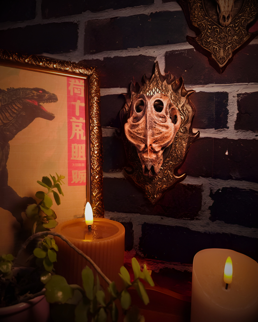 Crâne de dragon style Godzilla fixé sur une plaque murale ornée, vu de côté avec éclairage chaud, encadré par un cadre doré et une bougie, créant une atmosphère medieval décor et fantasy wall décor.