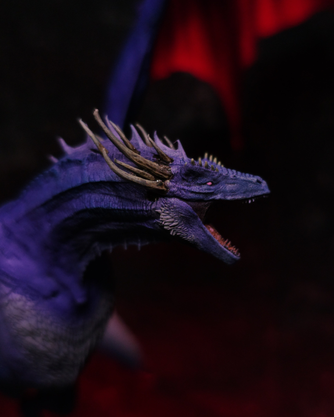 Gros plan de la figurine Dreamfyre de House of the Dragon, dragon violet aux cornes dorées, yeux roses et gueule ouverte, peint à la main en résine.