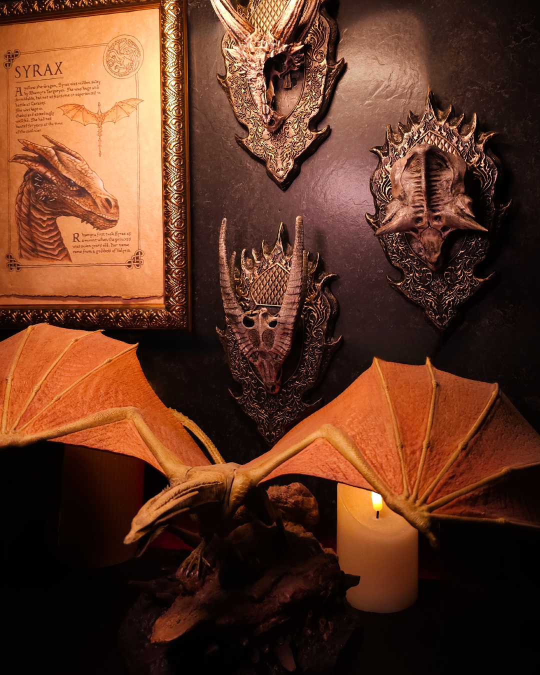 Trophée mural de crâne de dragon doré présenté dans un décor fantasy complet, avec figurine de dragon ailé, bougies et éléments médiévaux.