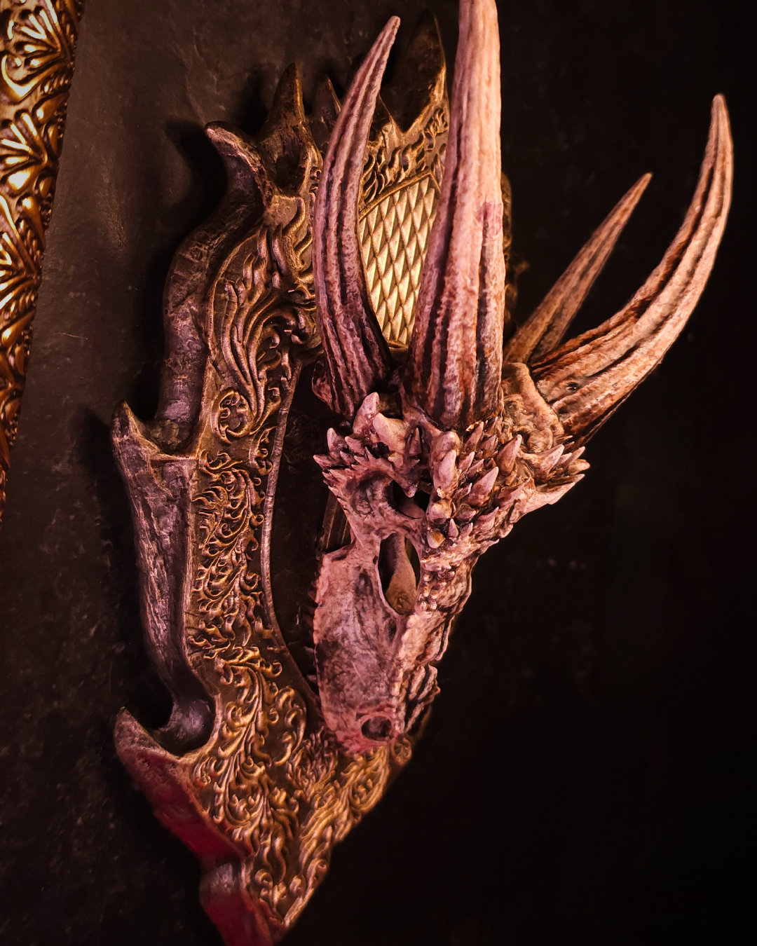Trophée mural représentant un crâne de dragon undead, avec support décoratif sculpté et finitions dorées, dans une ambiance sombre et médiévale.