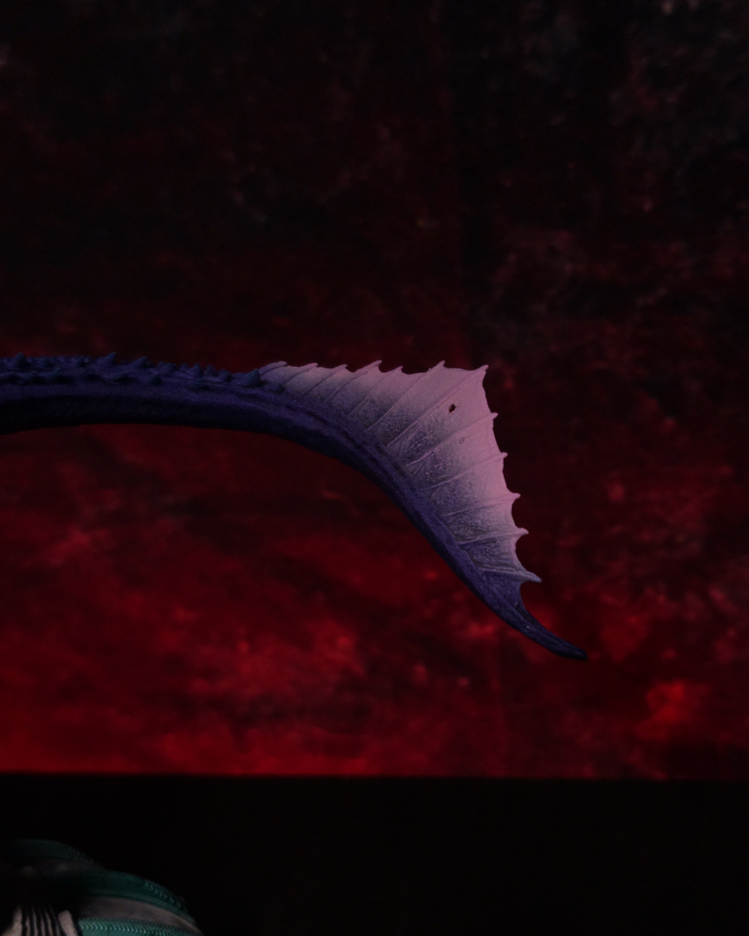 Détail de la queue de Dreamfyre, dragon de House of the Dragon, avec ses écailles violettes, ses épines dorsales et son extrémité en forme de nageoire.