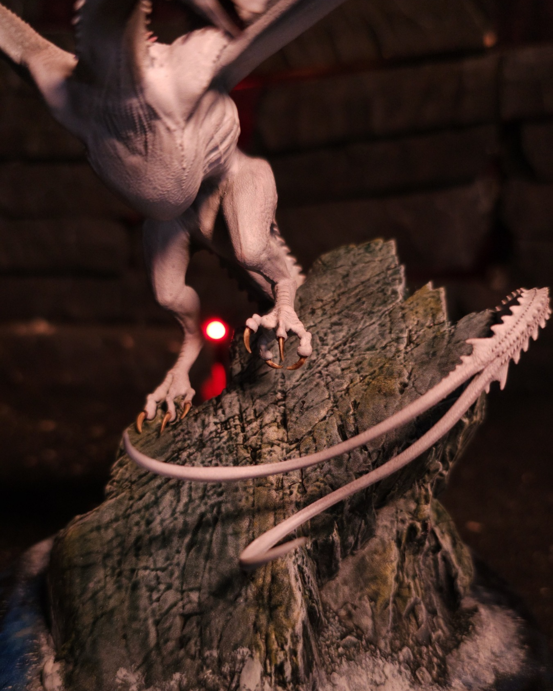 Gros plan des griffes du dragon Greyghost accrochées au rocher sculpté de son socle.