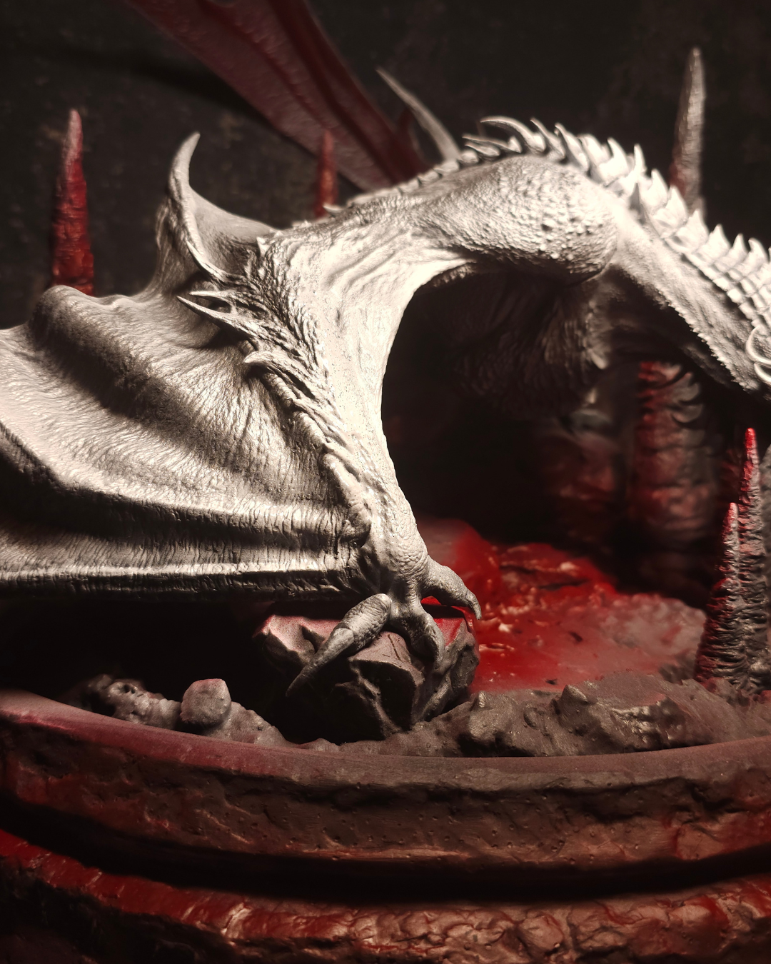 Vue latérale de la figurine de dragon Cannibal en résine brute sur un décor volcanique, inspirée de House of the Dragon, parfaite pour les amateurs de figurines de dragon et de peinture fantasy.