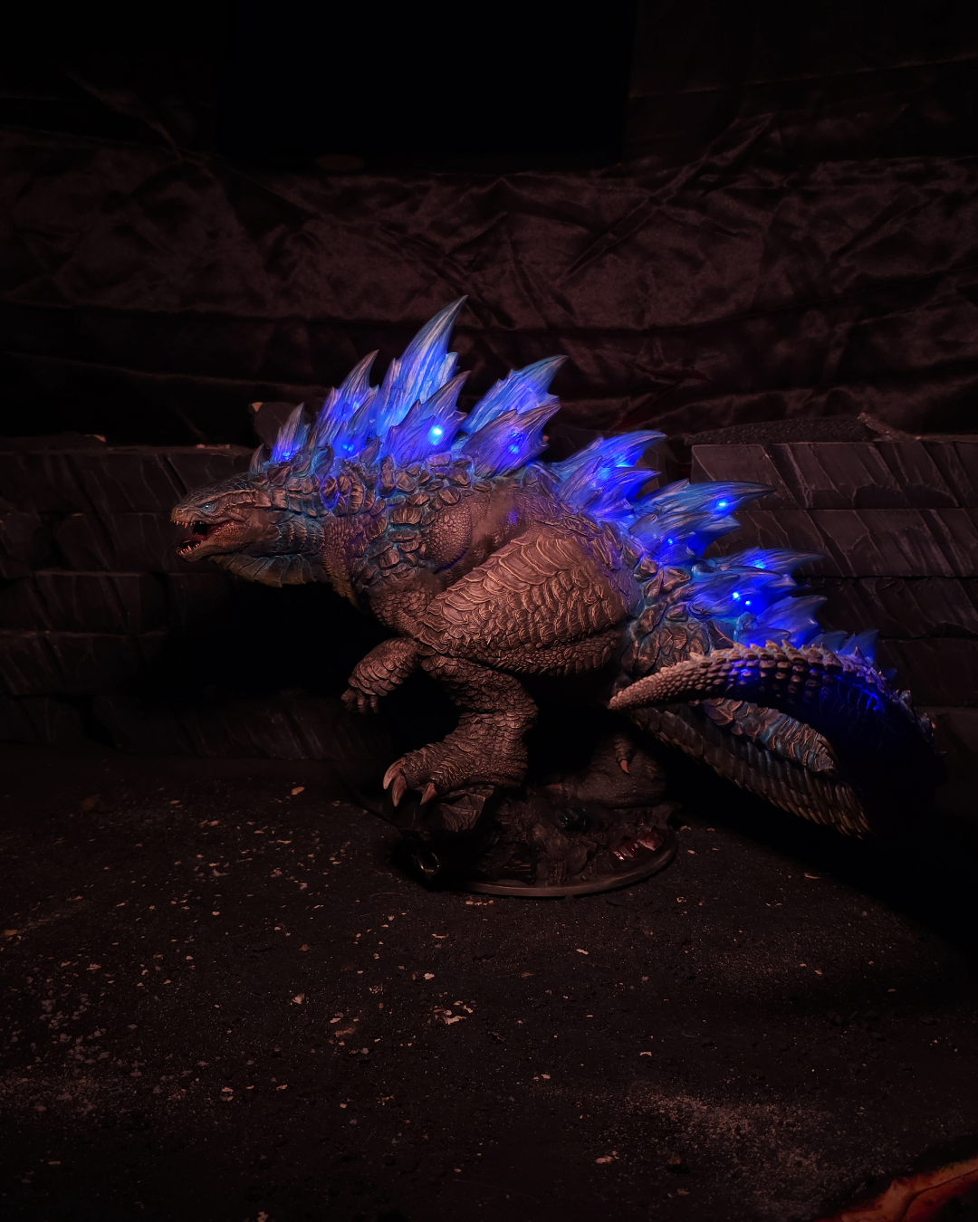 Figurine complète du King of Monsters posée sur un socle, montrant le corps massif, les pattes griffues et les plaques dorsales bleues lumineuses, idéale pour un fantasy décor de collection.