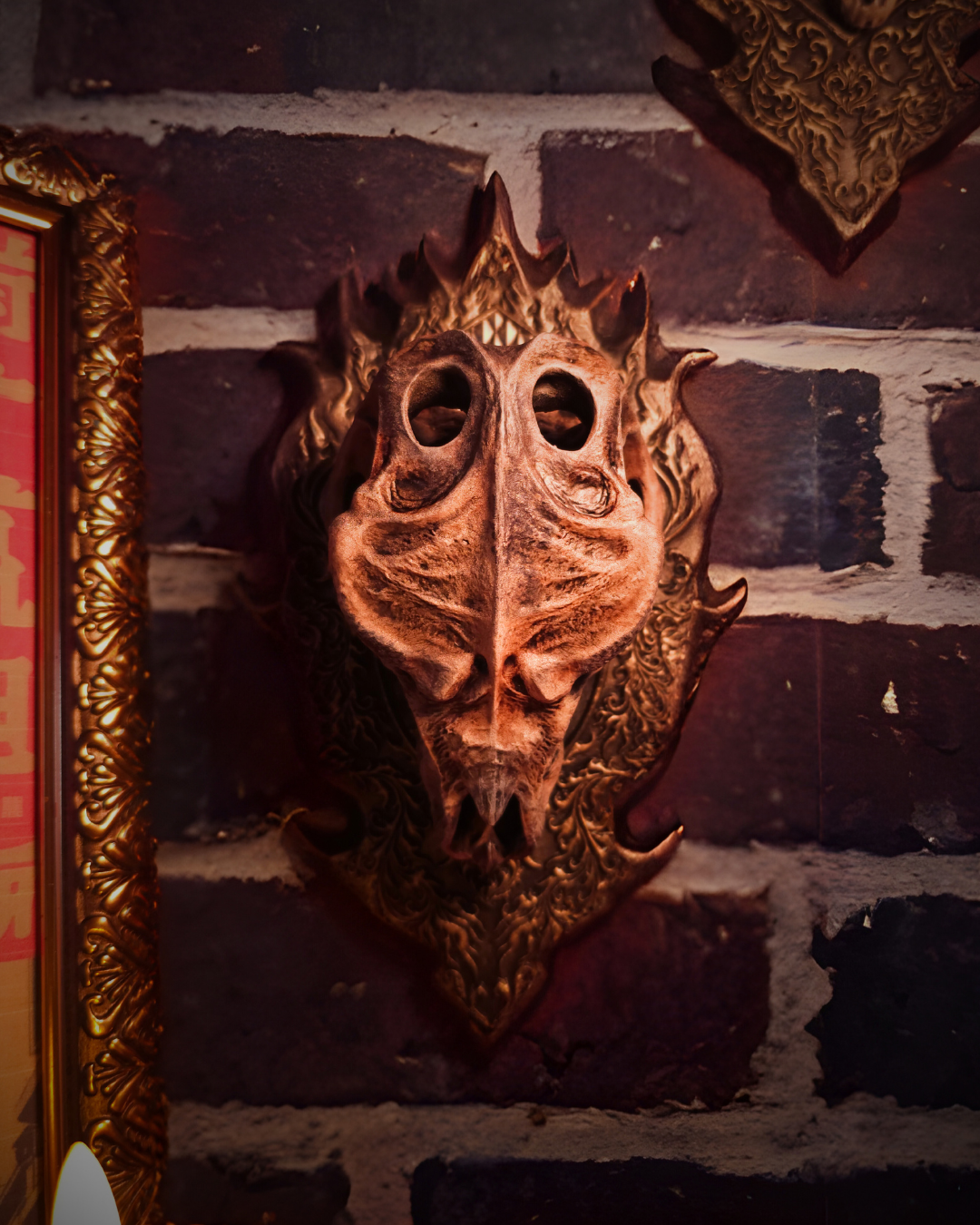 Vue rapprochée du crâne de dragon Godzilla monté en trophée mural, avec plaque ornée et mur en briques sombre, mettant en avant les détails sculptés du dragon head et l’ambiance gothic decor.