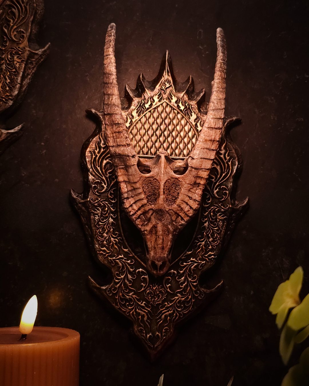 Crâne de dragon doré fixé sur un support mural sculpté, présenté comme un trophée fantasy avec plaque ornementale d’inspiration médiévale.