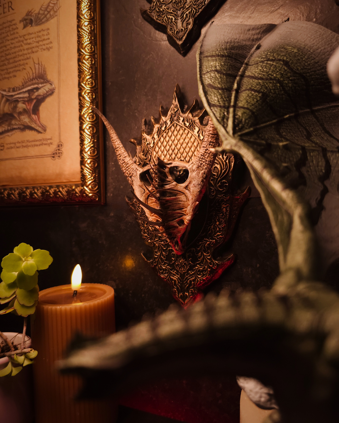 Crâne de dragon Moondancer exposé en trophée mural, partiellement encadré par une figurine de dragon et des bougies, renforçant l’atmosphère gothique et fantasy.