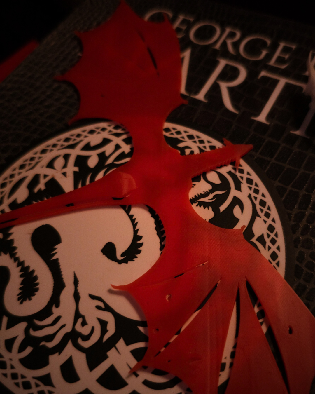 Détail du marque-page en résine rouge Meleys, montrant ses ailes de dragon découpées avec finesse.