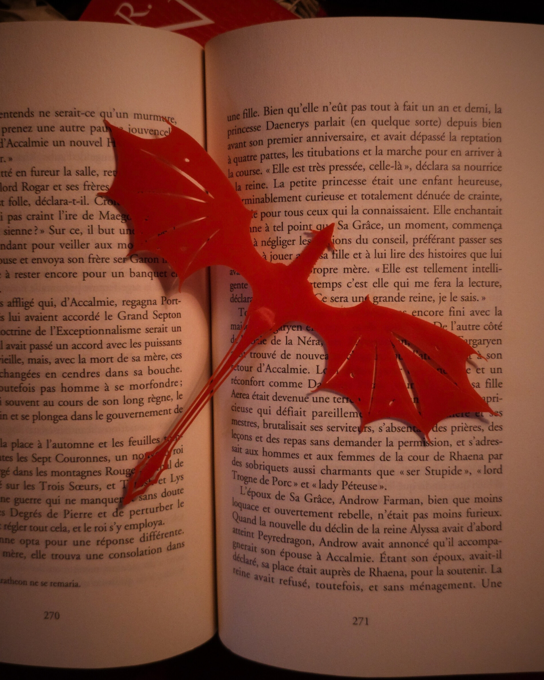 Marque-page dragon Meleys en résine rouge, inséré entre les pages d’un livre de la saga Targaryen.