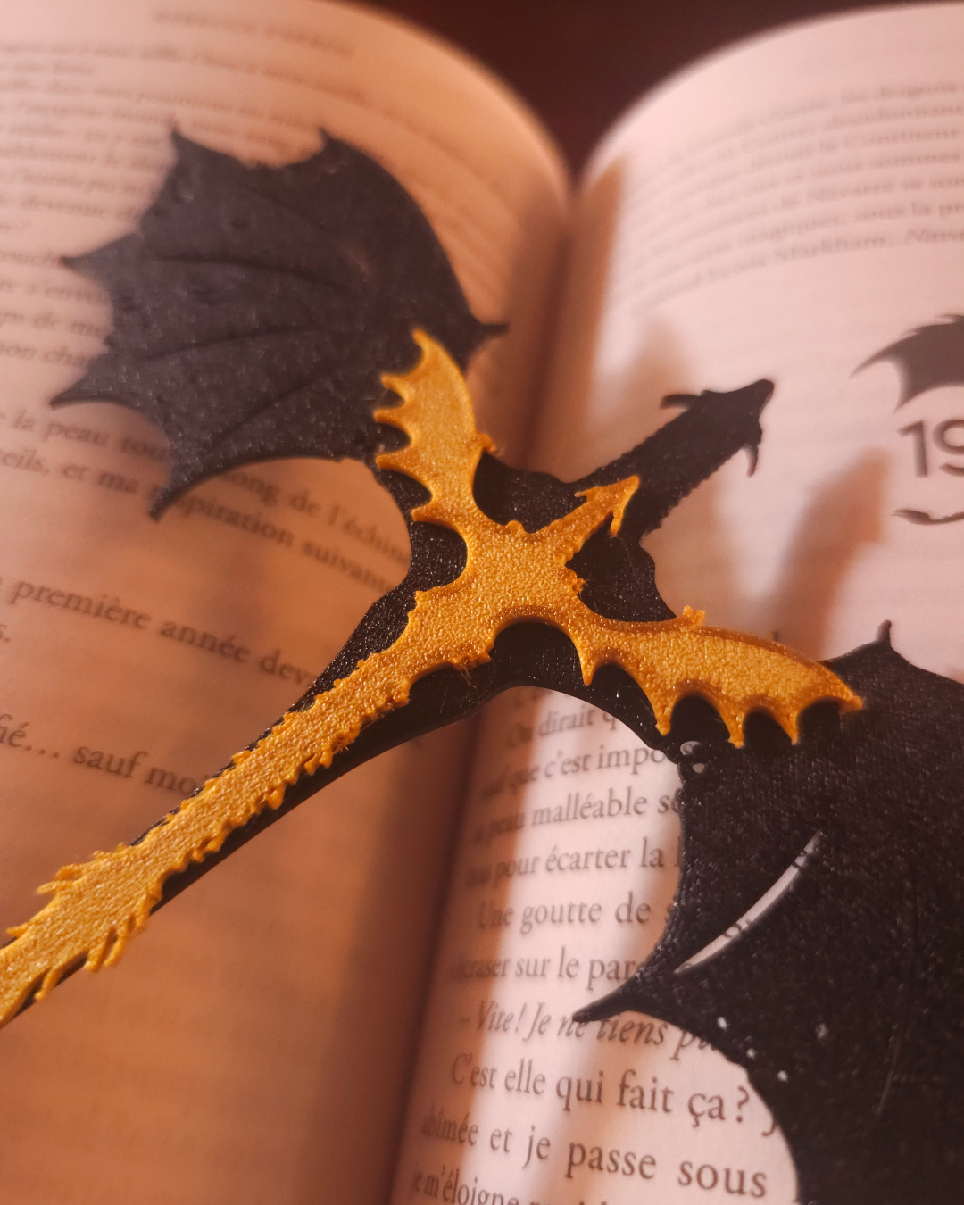Marque-page dragon inspiré de Tairn et Andarna de Fourth Wing, imprimé en 3D en PLA avec pince intégrée maintenant les pages d'un livre.