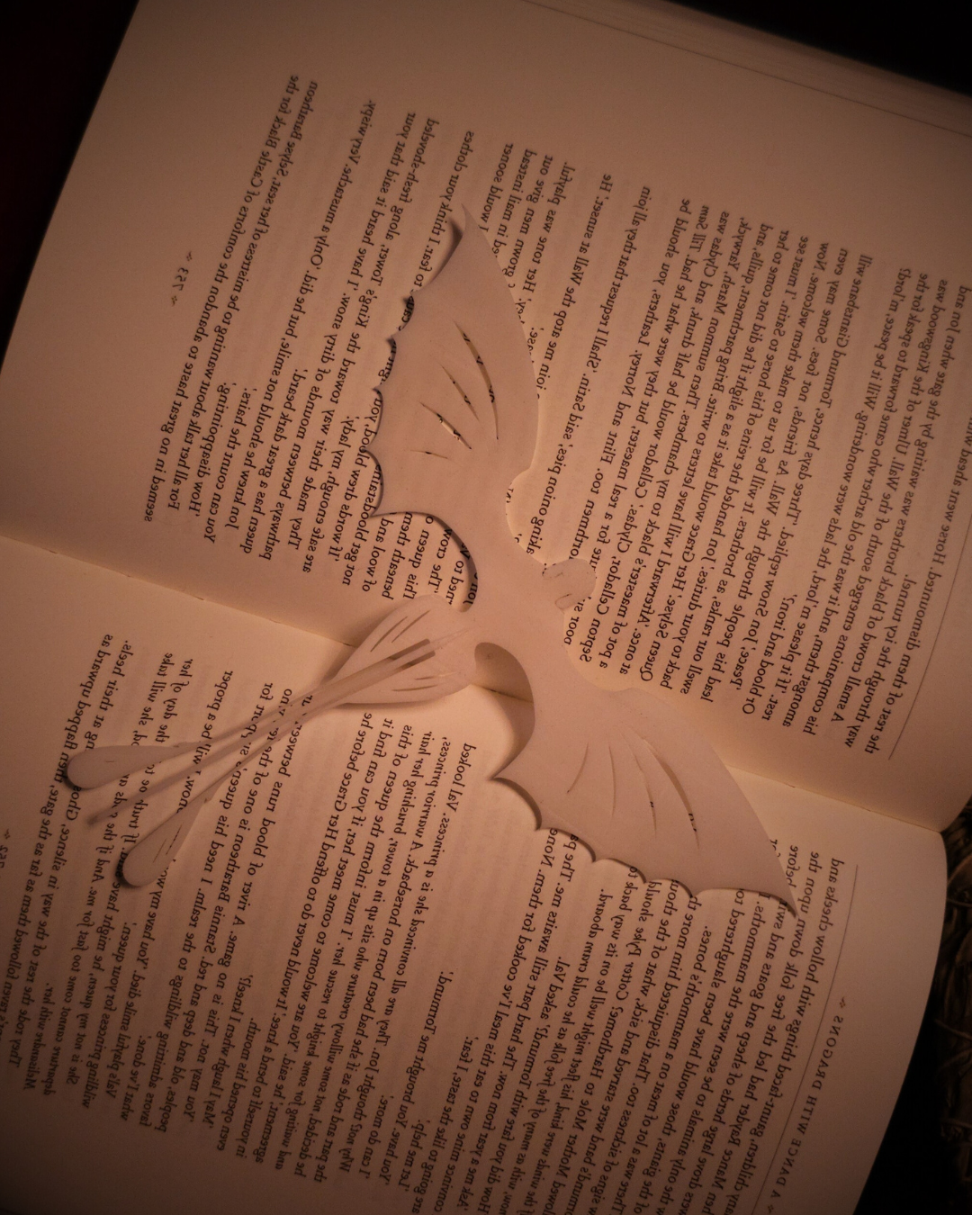 Marque-page dragon en résine blanche étendu sur les pages d’un roman, ailes sculptées rappelant la Furie Éclair.