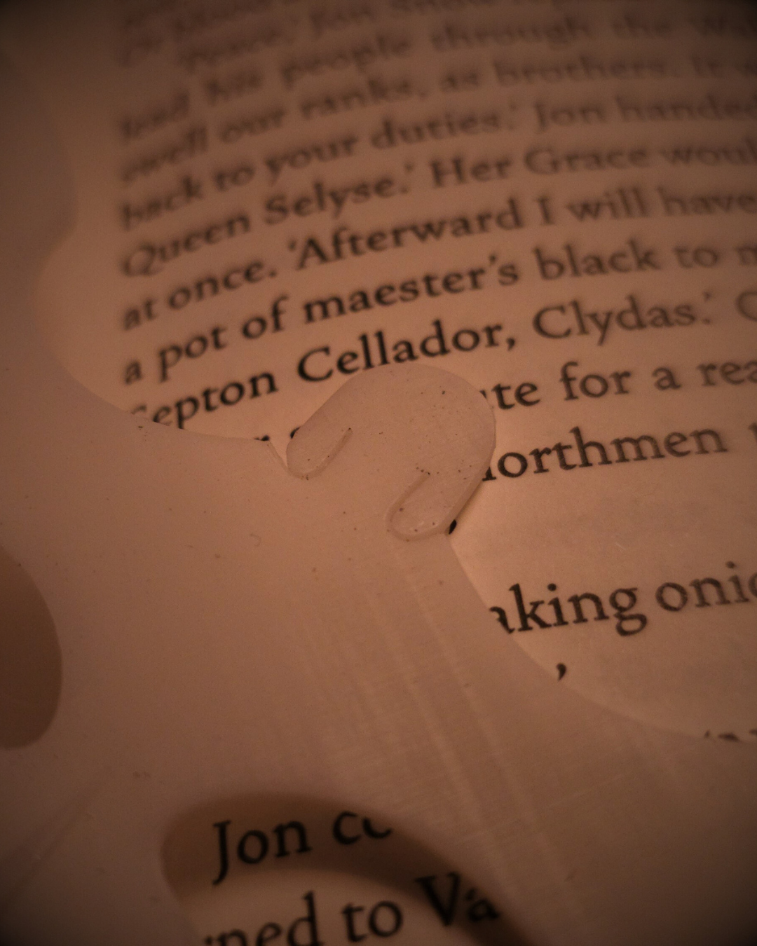 Gros plan sur la tête du marque-page blanc en résine, inspiré de la Furie Éclair de How to Train Your Dragon, posé sur les pages d’un livre.