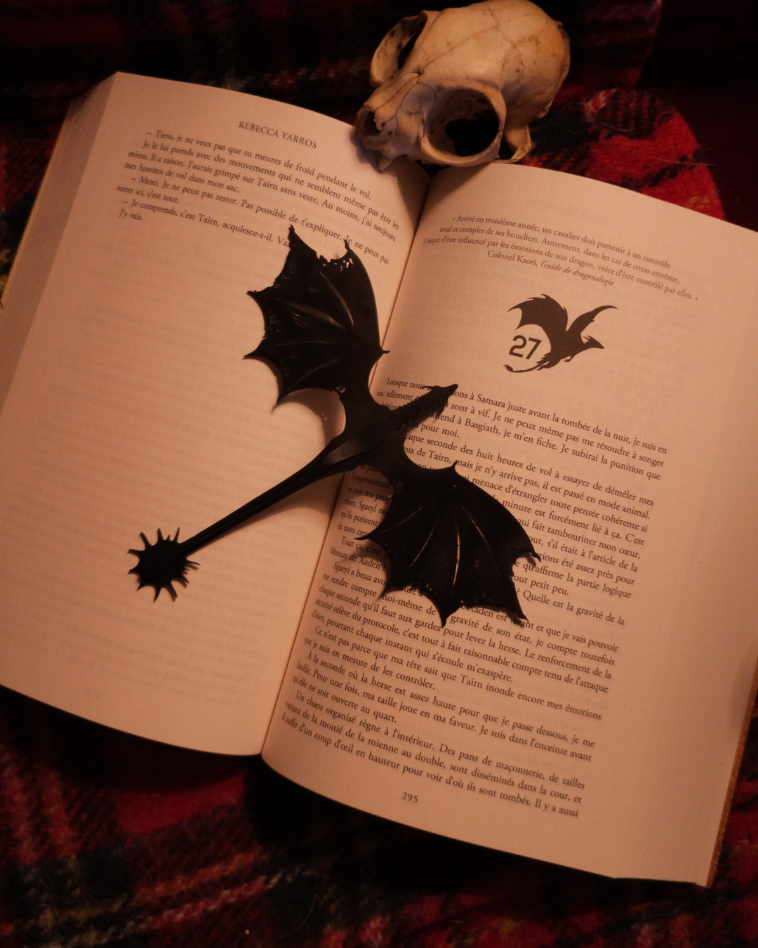 Marque-page dragon noir en résine 3D placé sur un livre avec un crâne décoratif, photo ambiance romantasy et fantasy pour lecteurs passionnés.