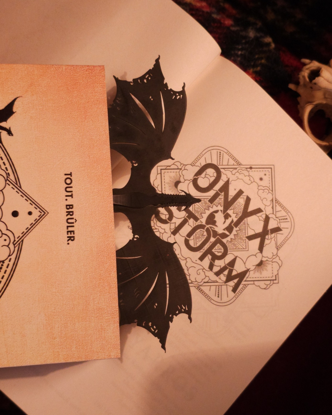 Vue latérale du marque-page dragon noir en résine maintenant un livre fermé, illustrant sa solidité et sa fonction antiglisse pour lecteurs fantasy.