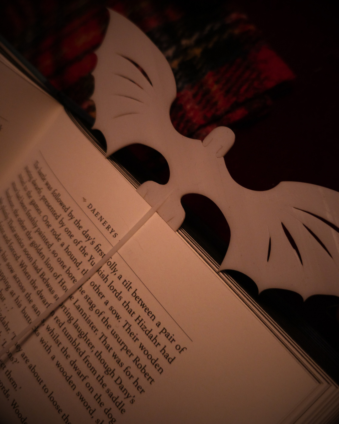 Vue rapprochée du marque-page dragon blanc, inspiré de la Light Fury, inséré dans un ouvrage ouvert.
