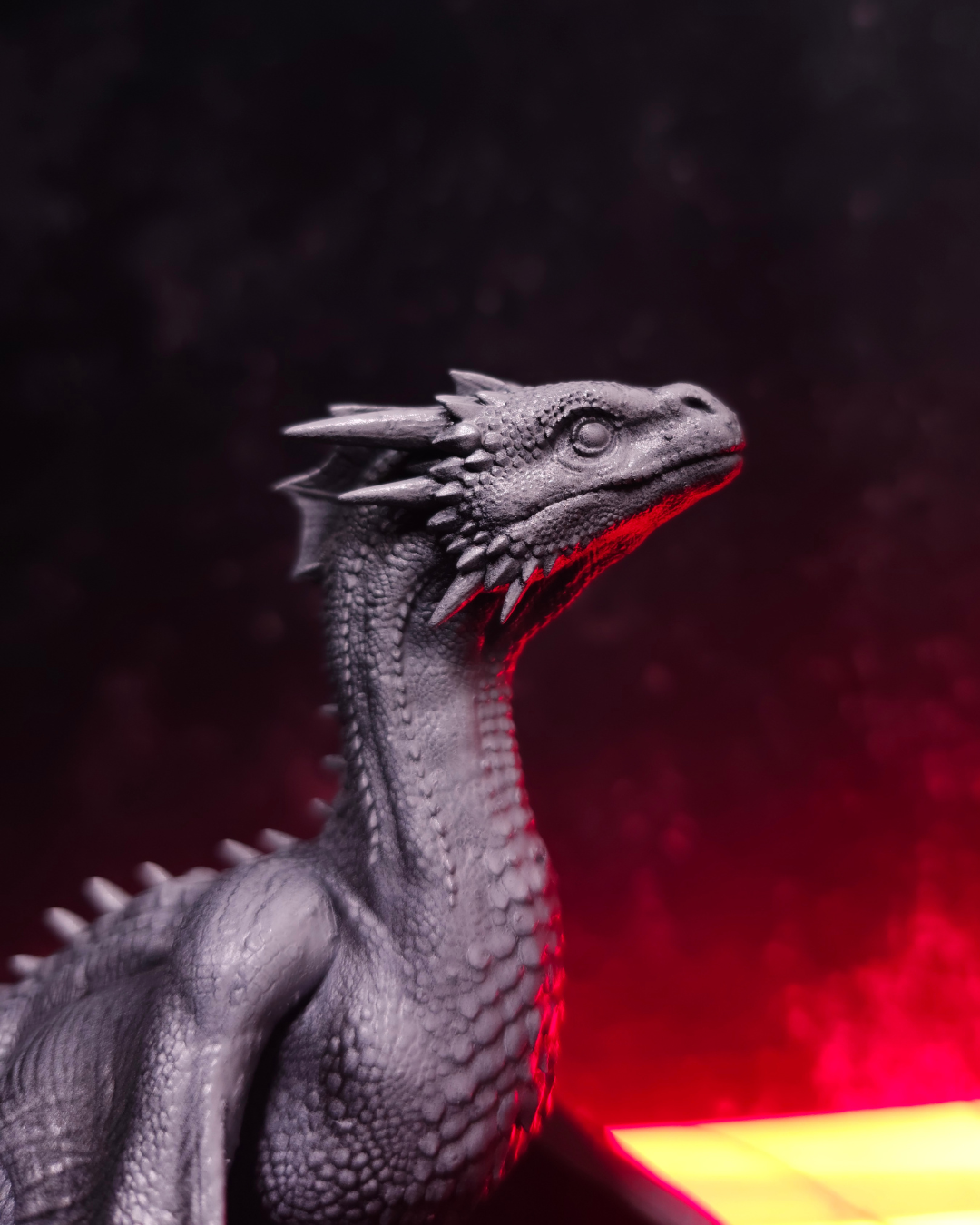 Minniature to paint showing a detailed baby dragon head in unpainted resin, fantasy miniature designed for hobby painting and custom color schemes.