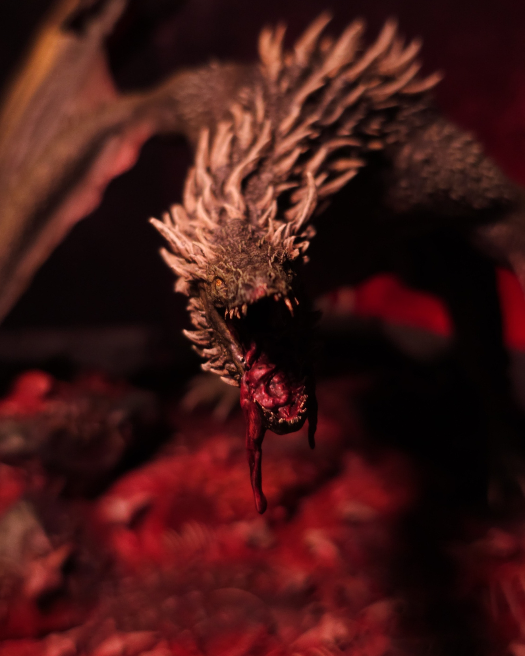 Gros plan sur le visage du dragon Sheepstealer rugissant, sa gueule dégoulinant de sang, sur fond rouge flamboyant pour un effet horrifique.