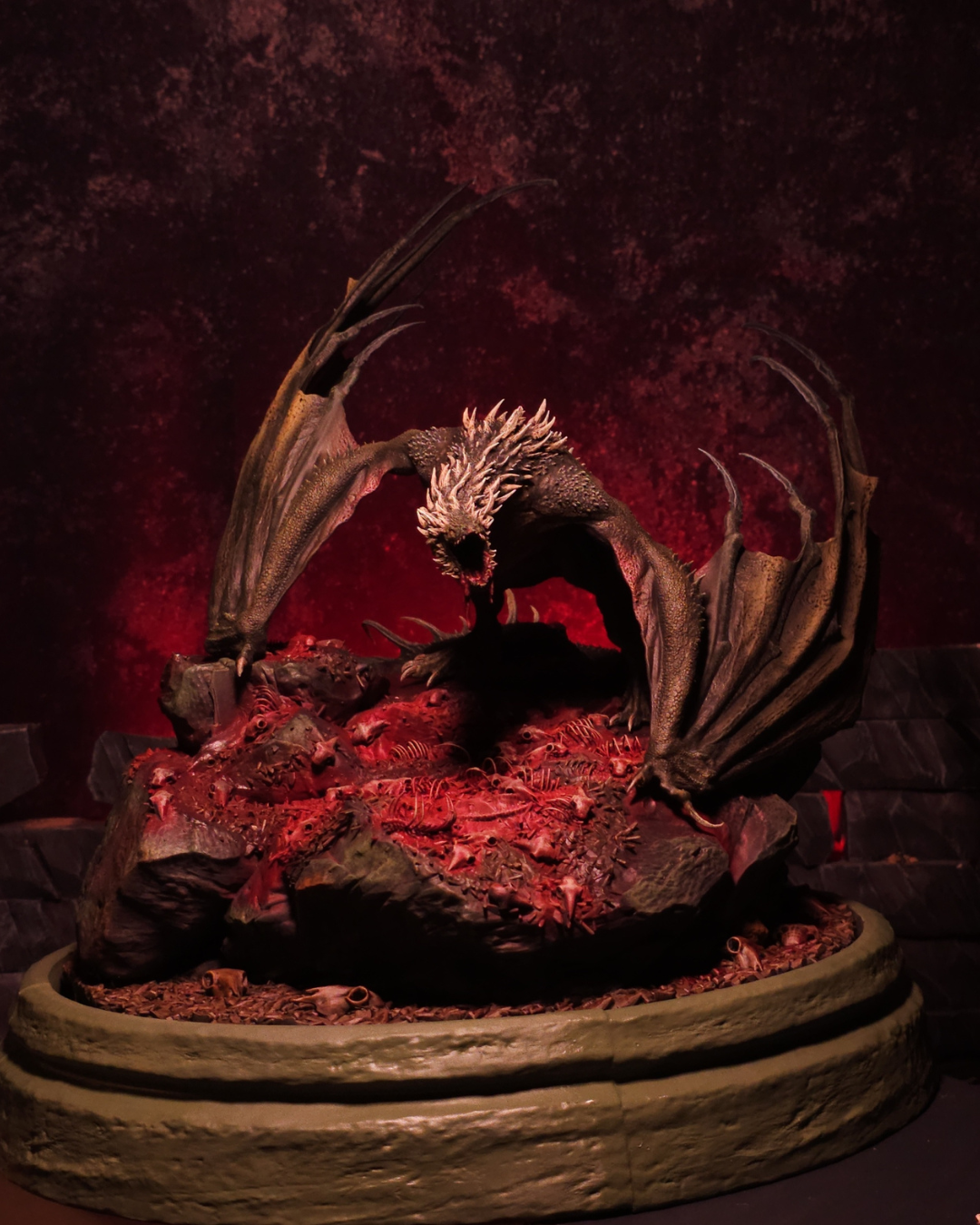 Figurine du dragon Sheepstealer inspirée de House of the Dragon, posée sur un socle jonché d’ossements, éclairée d’une lumière rouge sang pour une ambiance horrifique d’Halloween.