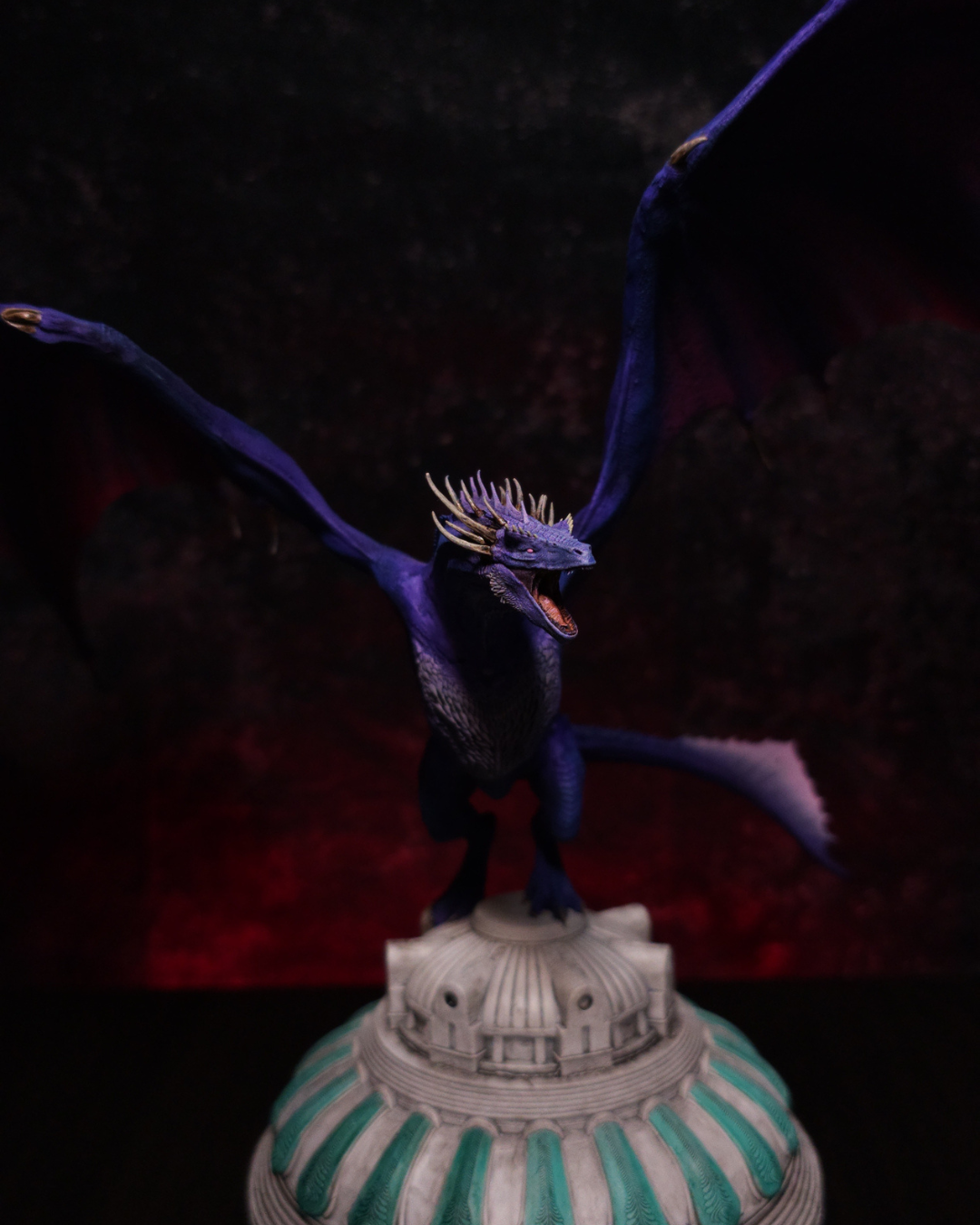 Figurine du dragon Dreamfyre de House of the Dragon vue de face, ailes violettes largement déployées, gueule ouverte et socle en forme de dôme.