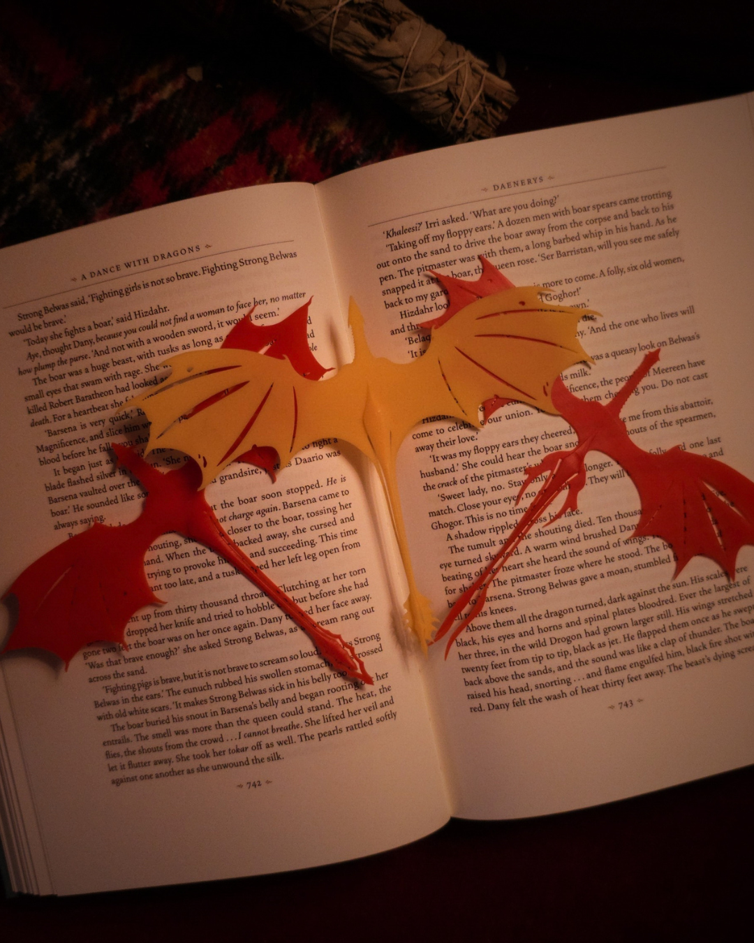 Trio de marque-pages dragons en résine inspirés de Caraxes, Meleys et Krokmou, mis en scène sur un livre ouvert.