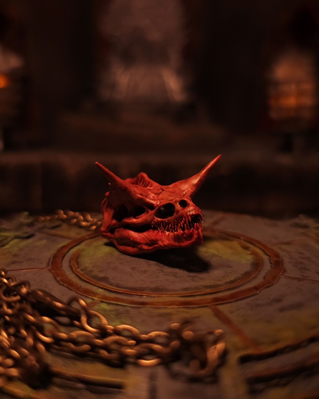 Crâne rouge sang du dragon Caraxes, la Vermine Rouge, présenté de face ; longues cornes effilées et dentition menaçante éclairées par une flamme tamisée.