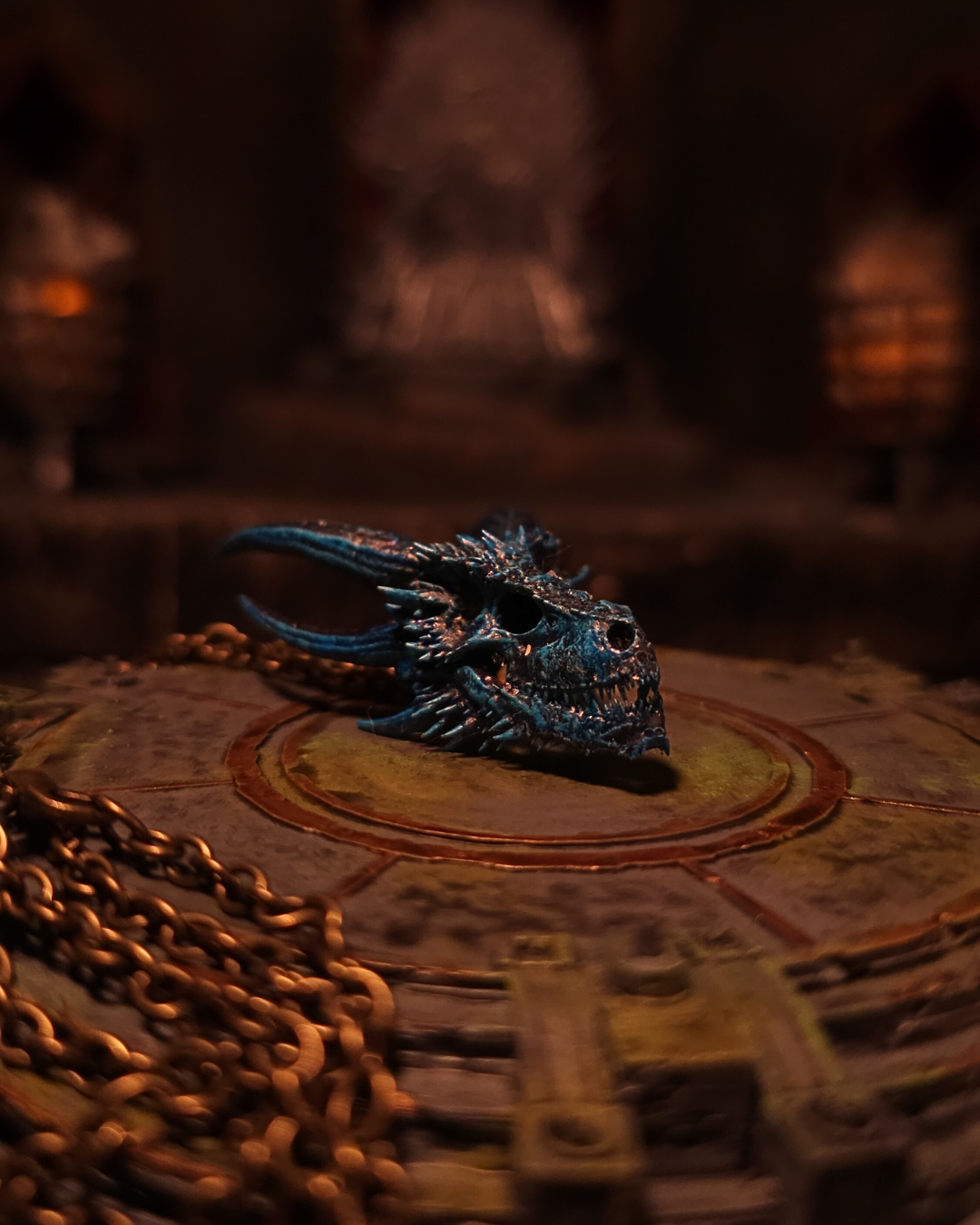 Pendentif crâne bleu glacé de Viserion, reflets azur rappelant la résurrection du Roi de la Nuit, reposant sur une dalle antique à la lueur des torches.
