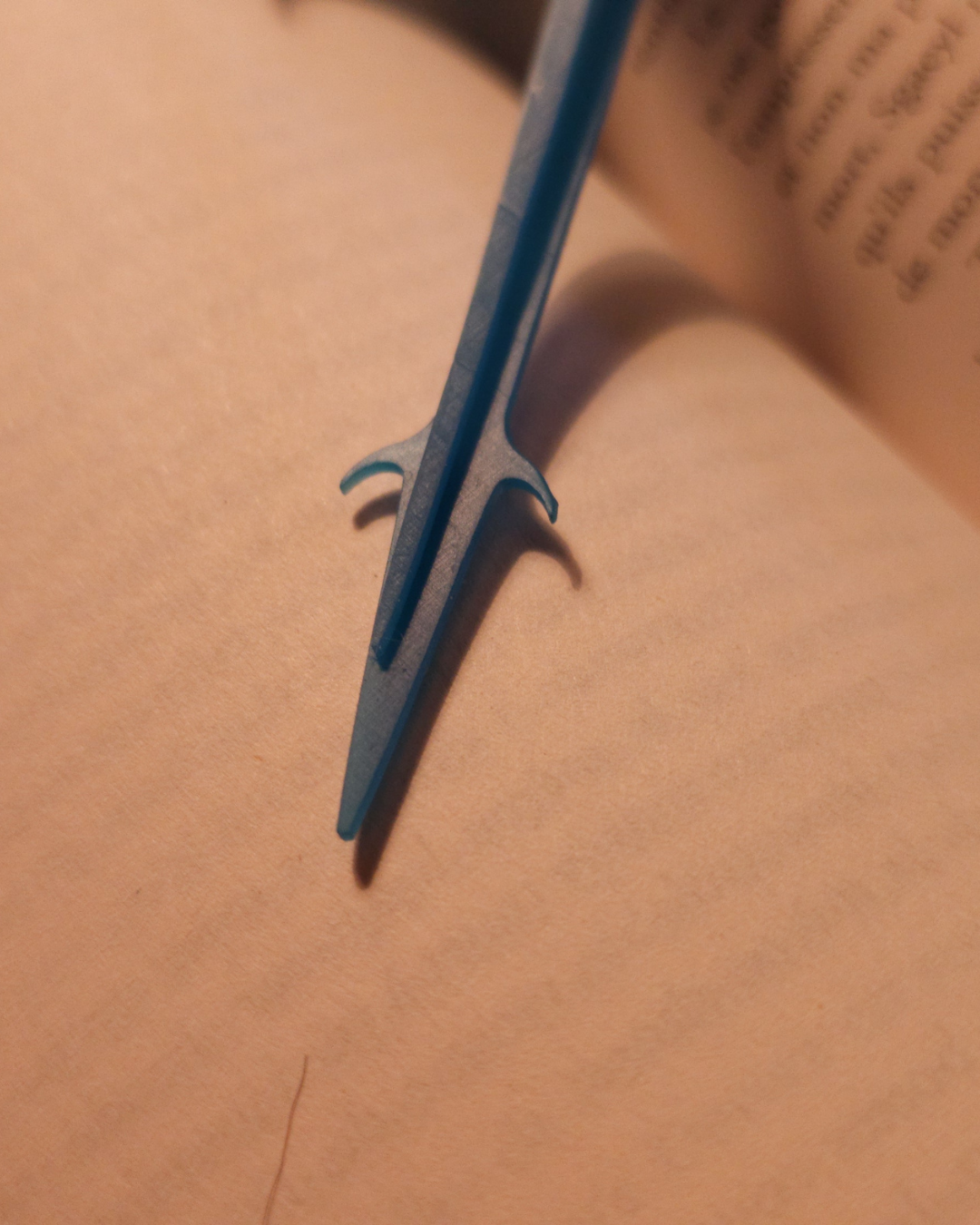 Gros plan sur l’extrémité de la queue du marque-page dragon bleu “Dagger-tail”, imprimé en résine 3D. Accessoire souple et robuste, parfait pour les lecteurs de fantasy et amateurs de figurines de dragon.