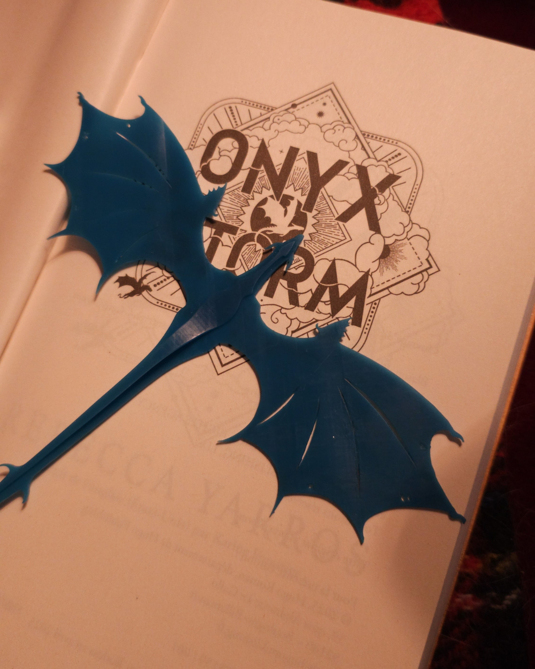 Dragon bleu en résine posé sur une page illustrée Onyx Storm, évoquant l’univers de Fourth Wing. Marque-page fantasy détaillé et idéal pour les lecteurs passionnés de dragons.